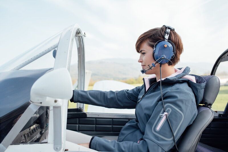 person sitting inside of a plane cockpit wearing an aviation headset