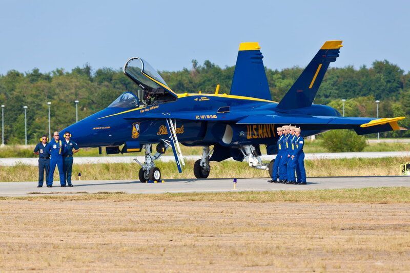 blue angels plane on the ground surrounded by pilots.