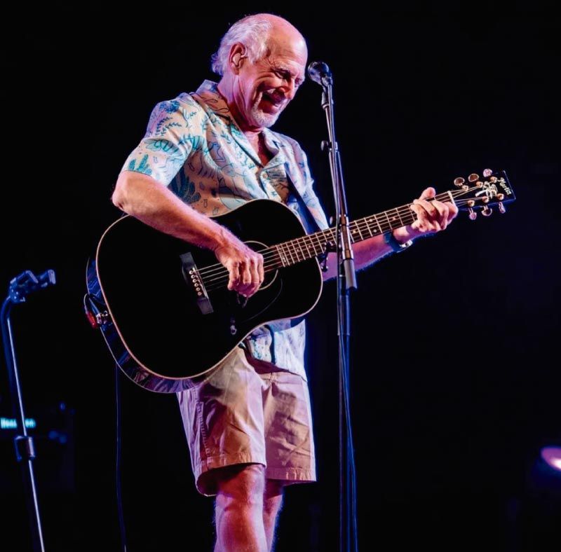 celebrity jimmy buffett playing the guitar on stage