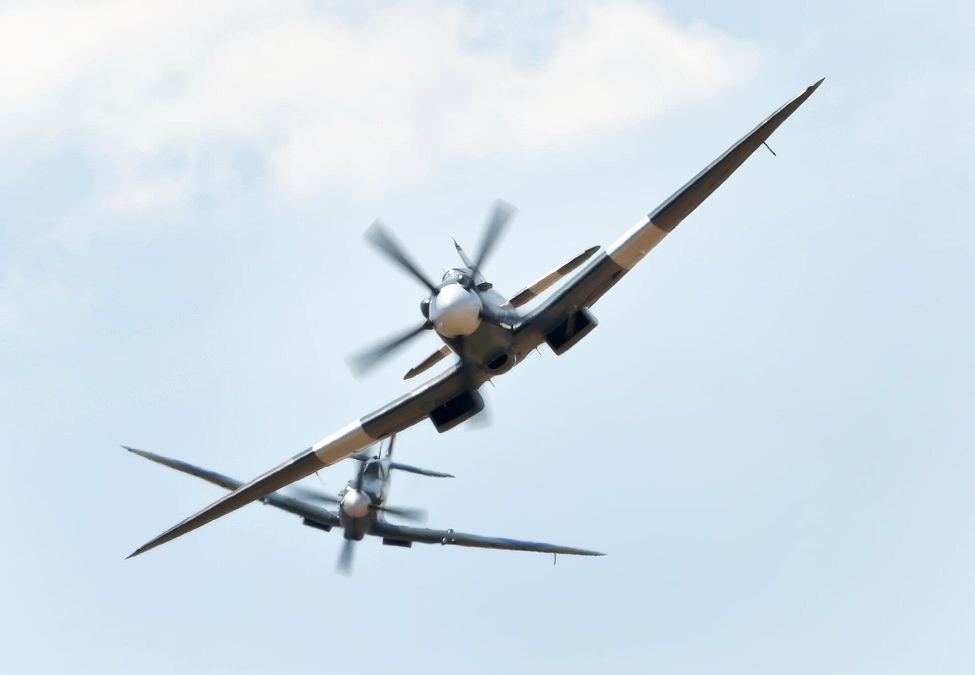 two spitfire planes flying into a dogfight