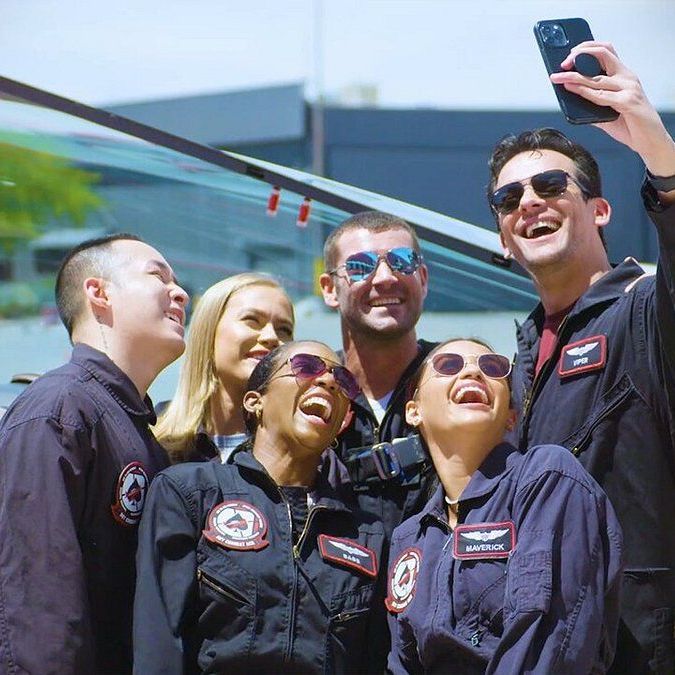 A group of people are taking a selfie with a cell phone.