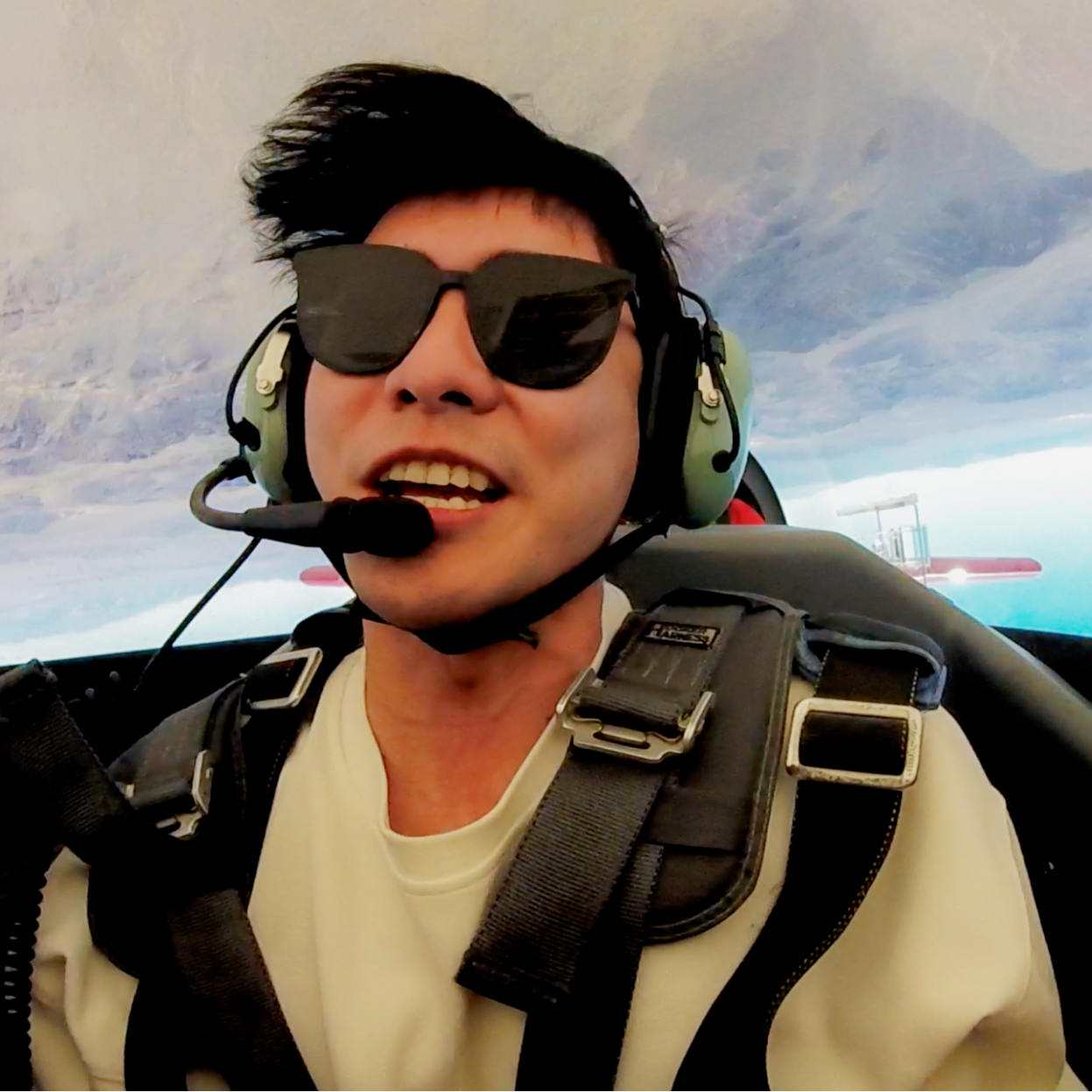 A man wearing sunglasses and headphones is sitting in a plane