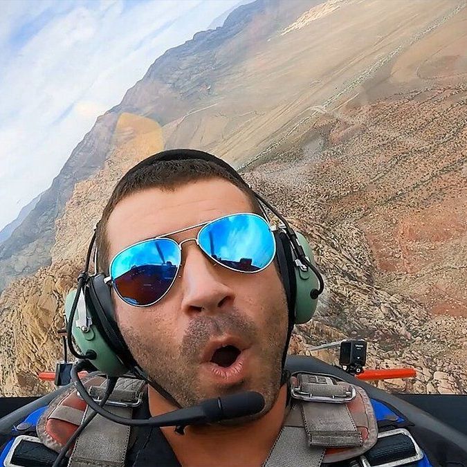 A man wearing sunglasses and headphones is sitting in a plane