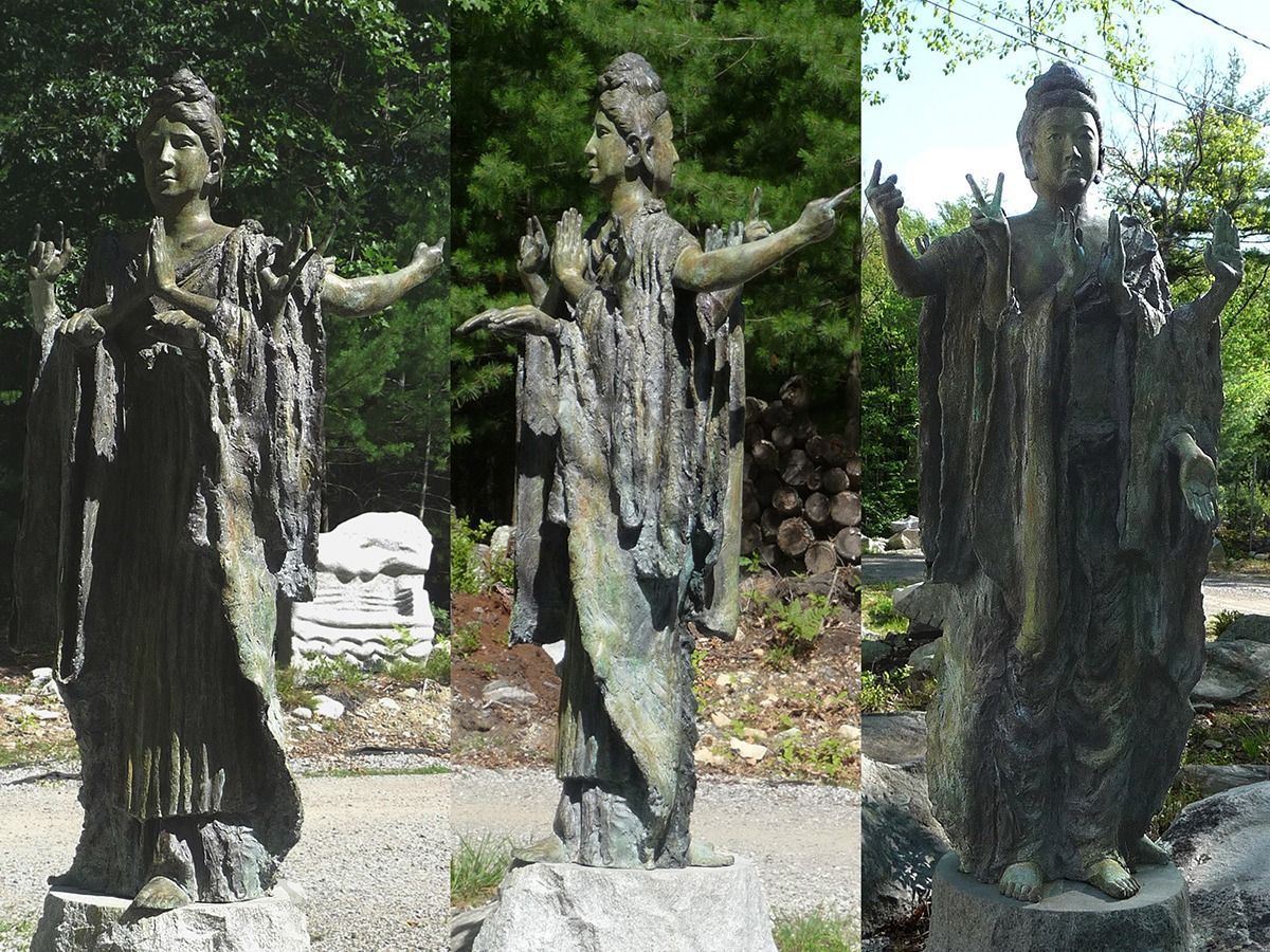 Three bronze sculptures of figures with outstretched arms stand on stone pedestals in a wooded area. The statues have long robes and headdresses.