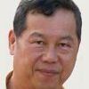 Smiling Asian man with short, dark hair against a light background.