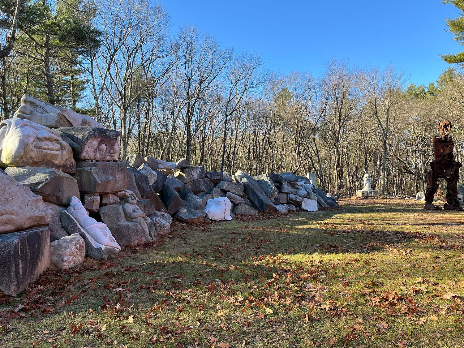 A large red building with multiple windows. A wooden ladder reaches the roof, and a person stands at the top. Trees and grass surround the building.