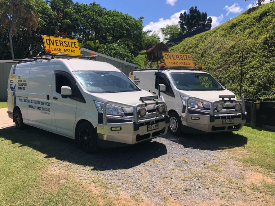 Two White Vans Are Parked Next to Each Other in A Grassy Area — Col Adamson Transport Pilot Services In Farleigh, QLD