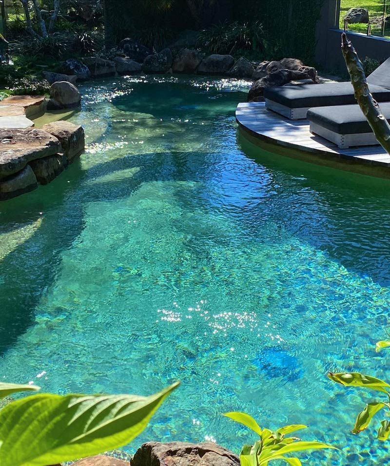 A Swimming Pool Surrounded By Rocks And Plants Design — Byron Bay Luxury Pools in Myocum, NSW