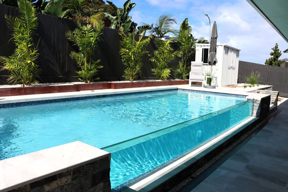 A Large Swimming Pool With A Clear Bottom Is Surrounded By Trees And A Fence — Byron Bay Luxury Pools in Myocum, NSW