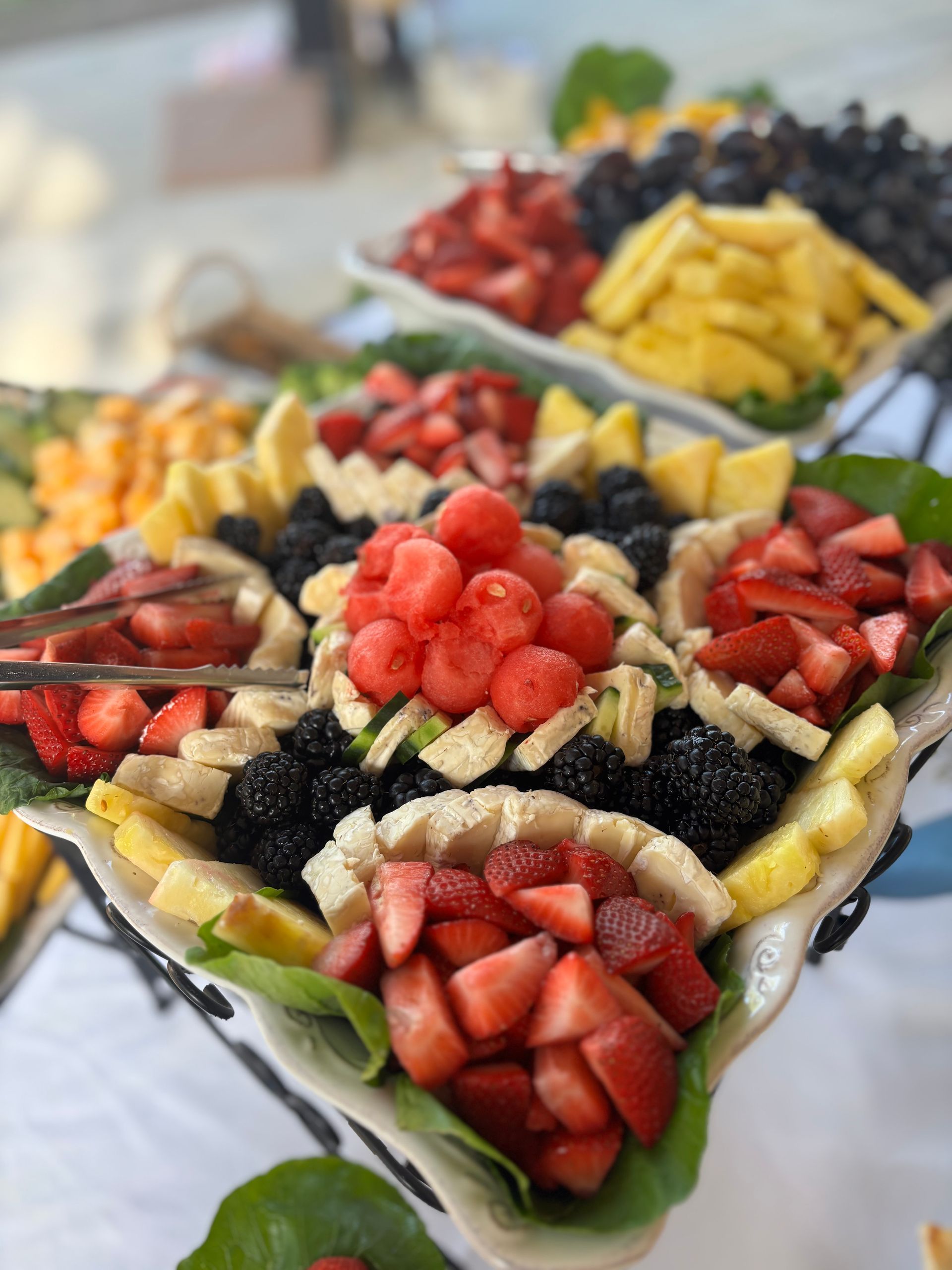 A fruit platter with strawberries, watermelon, blackberries, and bananas arranged on a table.