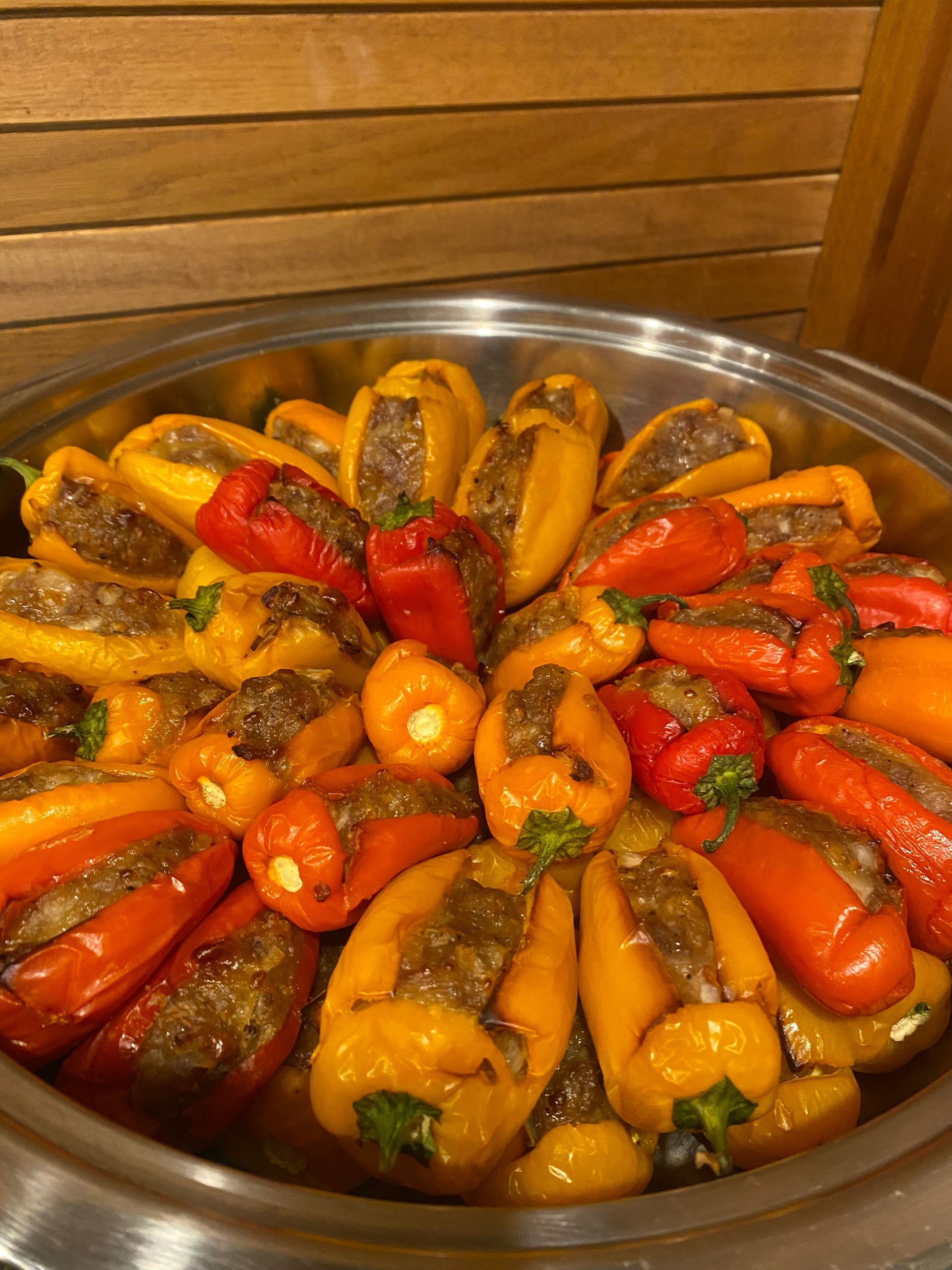 A metal bowl overflows with colorful, stuffed mini peppers, baked to golden perfection.