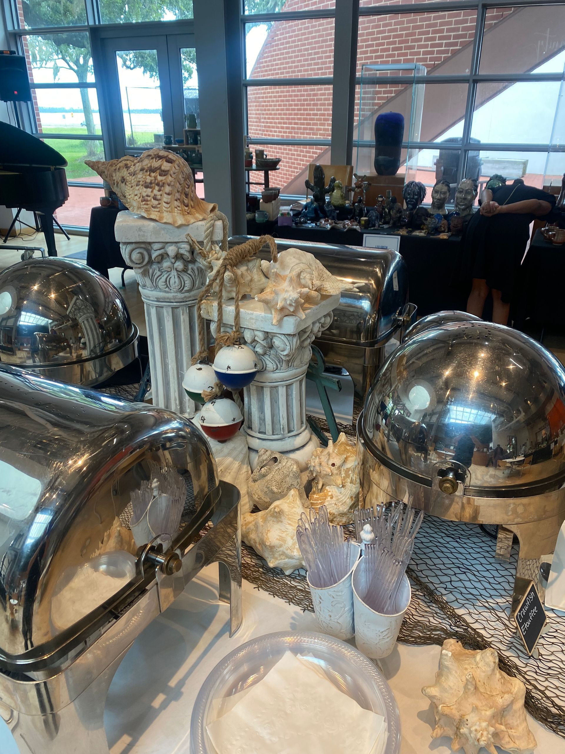 Buffet setup with silver chafing dishes, decorated with coral, columns, and nautical ornaments.