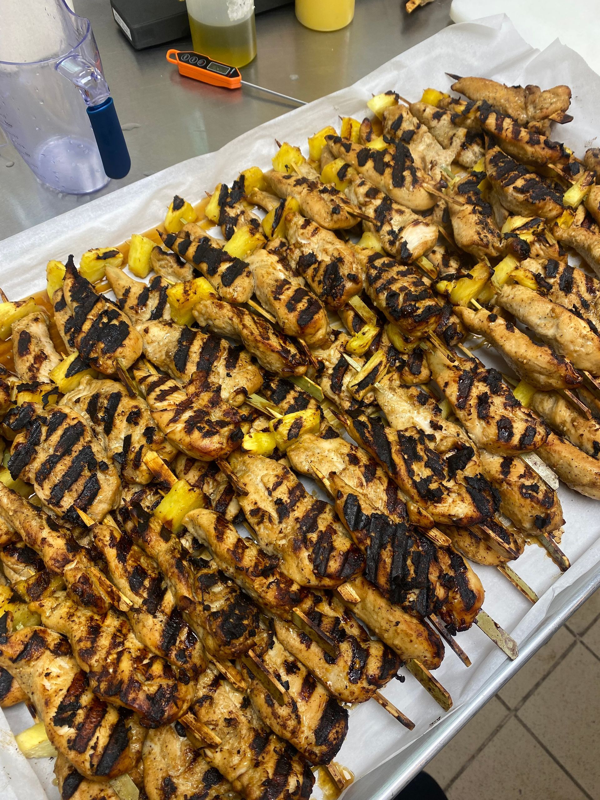 Grilled chicken and pineapple skewers arranged on a tray, ready to serve.