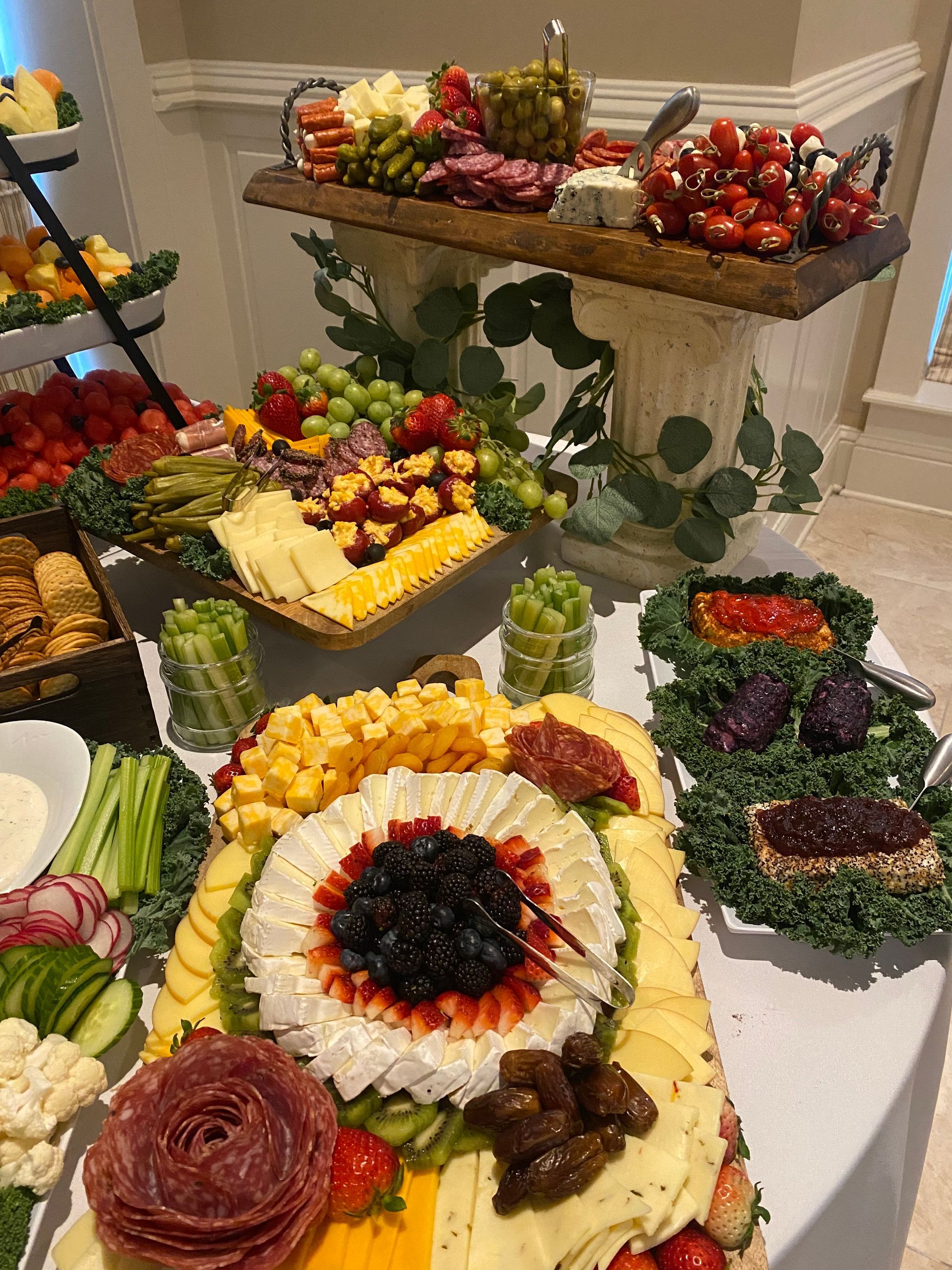 A lavish charcuterie spread on a table with various cheeses, meats, fruits, and vegetables.