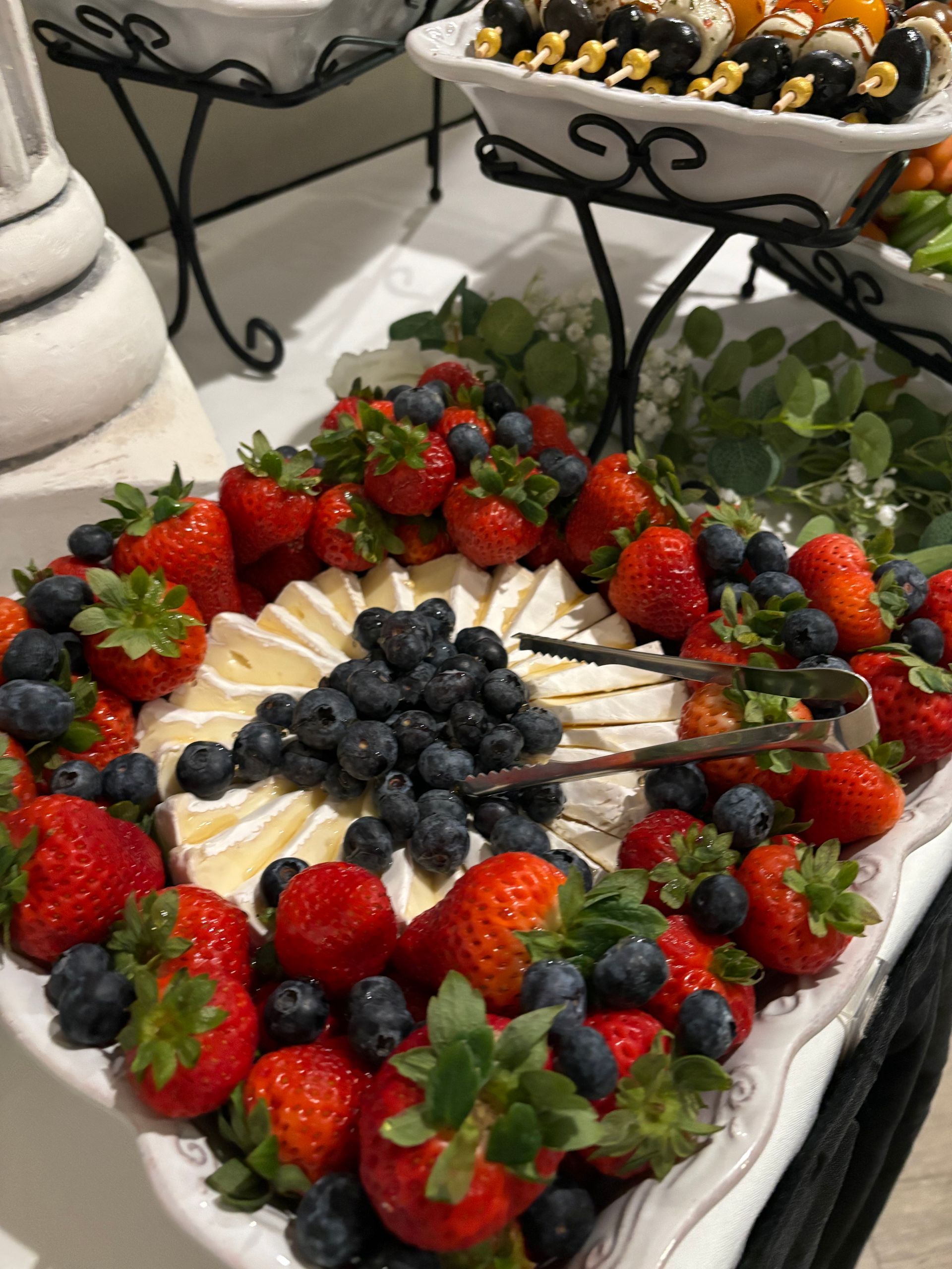 A platter of strawberries, blueberries, and brie cheese, arranged for a catered event.