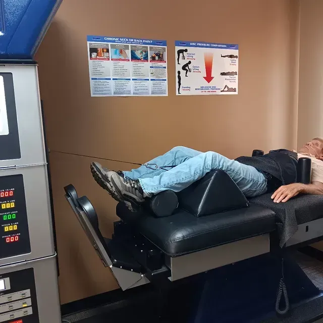 Person lying on a black exam table in a clinic room, with informational posters on the wall.