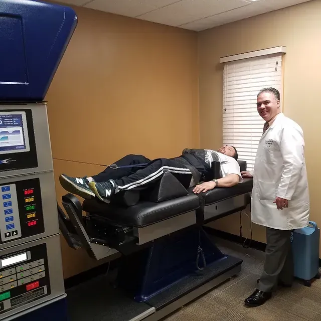 Patient on a medical exam table while a clinician stands nearby in a clinic room.