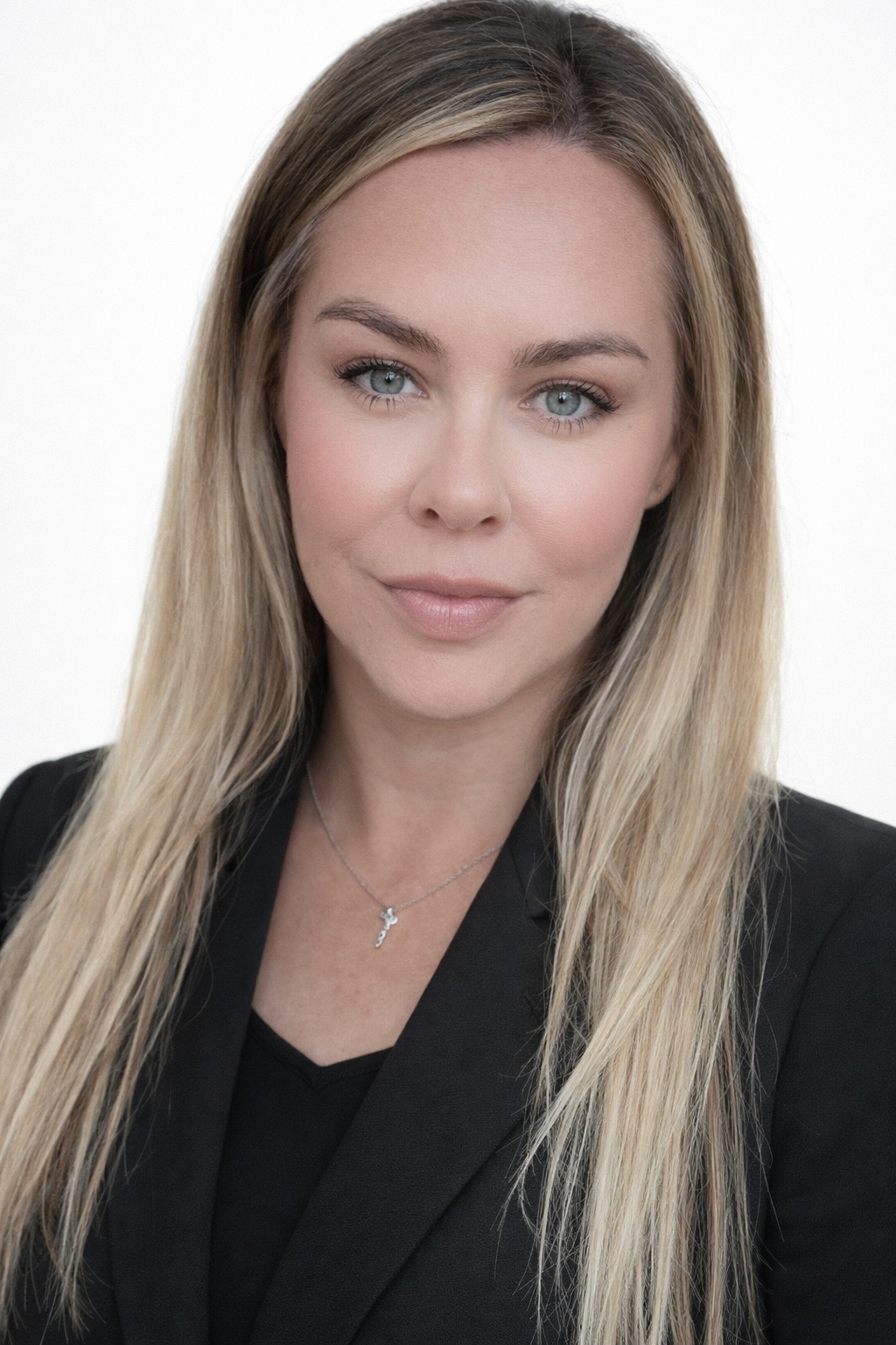 Blonde woman wearing a black blazer smiles, looking at the viewer.