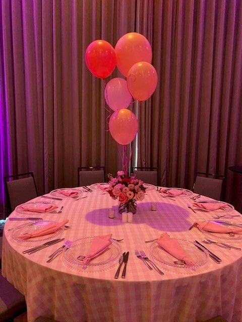 A foral pink centerpice with five helium pink balloons floating above the flowers.