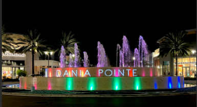 The Dania Pointe center fountain with lights on at night.