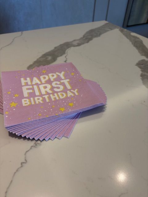 Pink paper  napkins that reads Happy First Birthday.