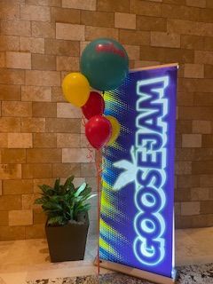 Helium balloons floating next to a WaWa Goosejam sign.