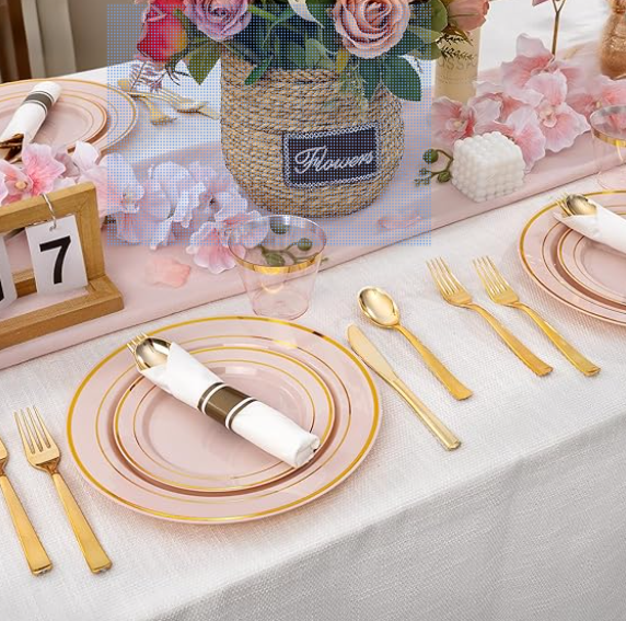 A party place setting with pink plastic plates, gold silverware