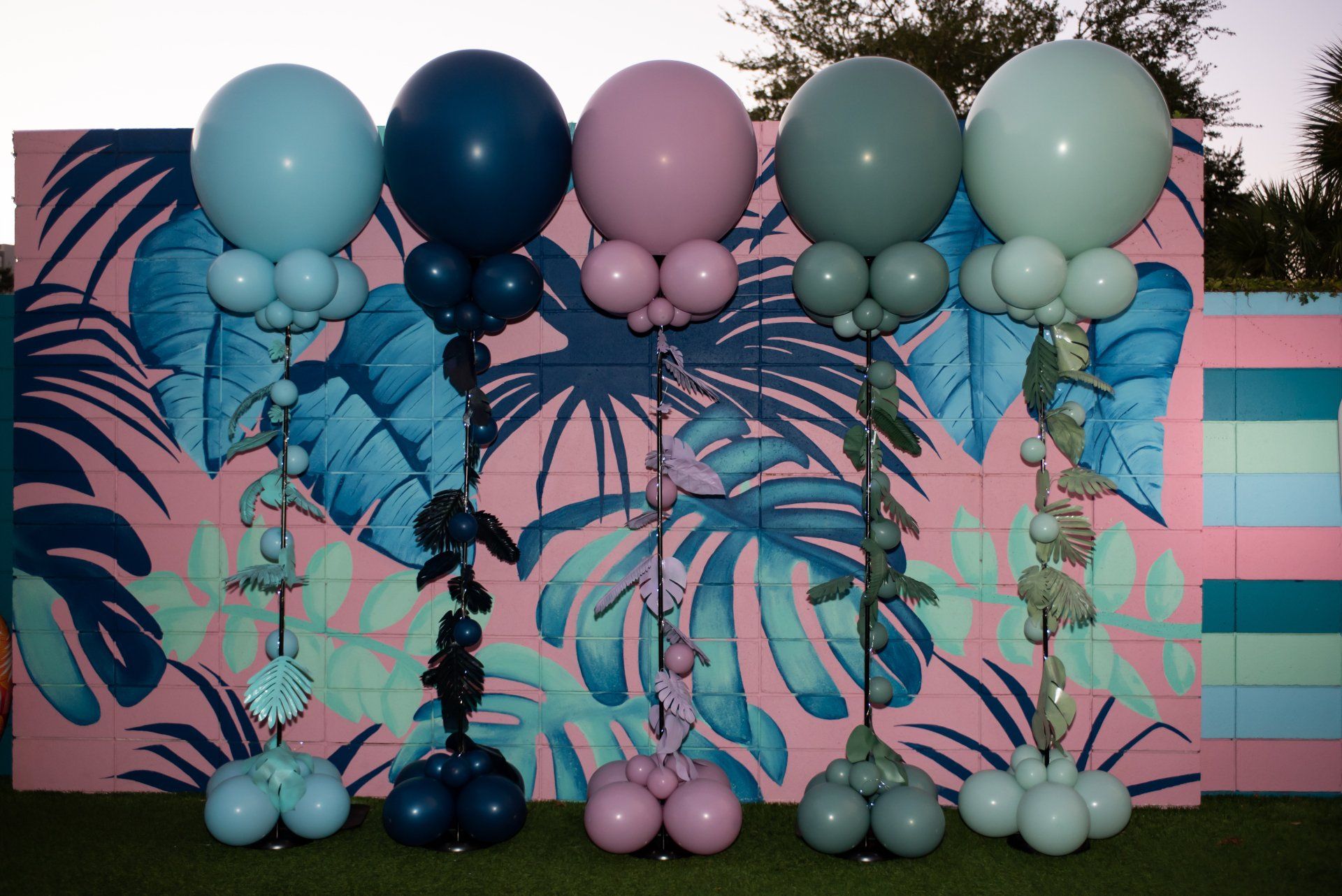 Four large 3' balloons floating above the grassy area near a pool.