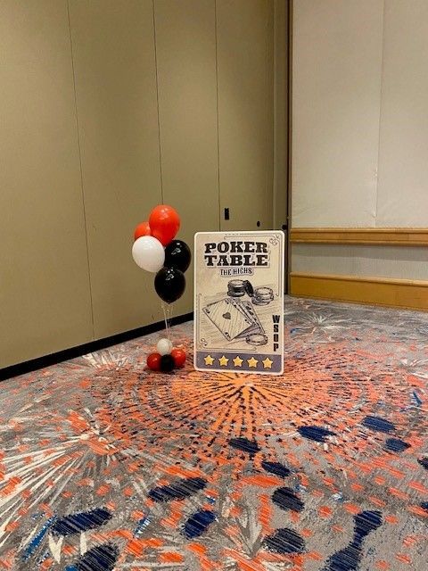 Red, black and white helium balloons next to a large playing card.