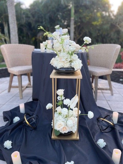 A picnic table next to the pool with white flowers and candles.  Curated by An Elegant Picnic in South Florida.