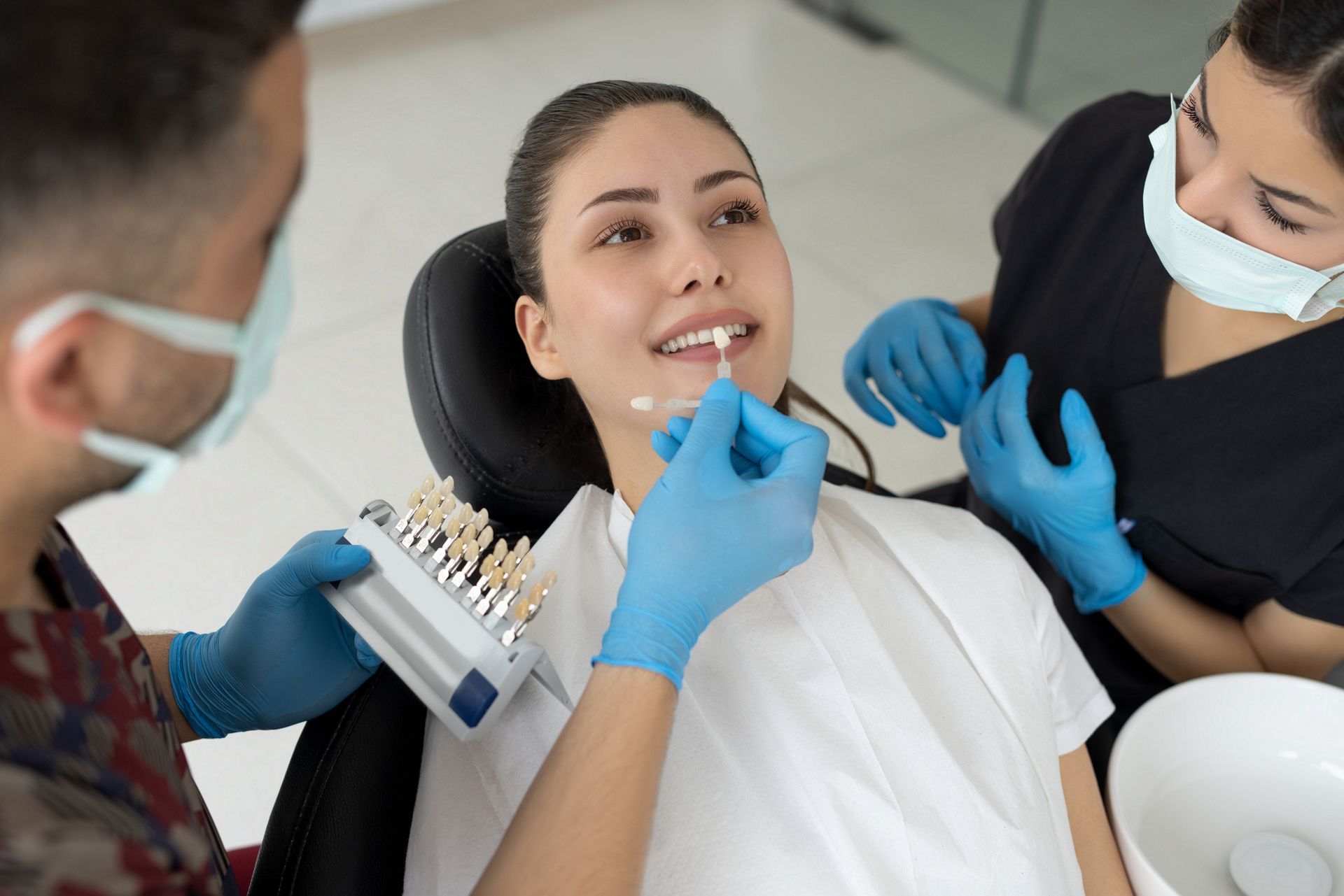 A woman in a dentist clinic choosing a shade of dental veneers.