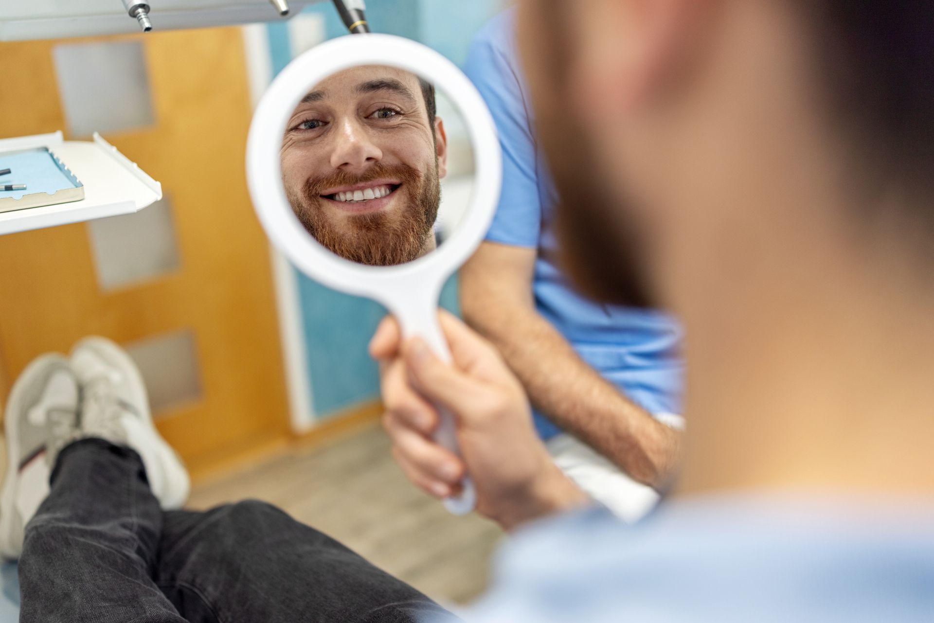 A smiling patient looking at the mirror, after an all-on-4 dental implants procedure at a clinic.