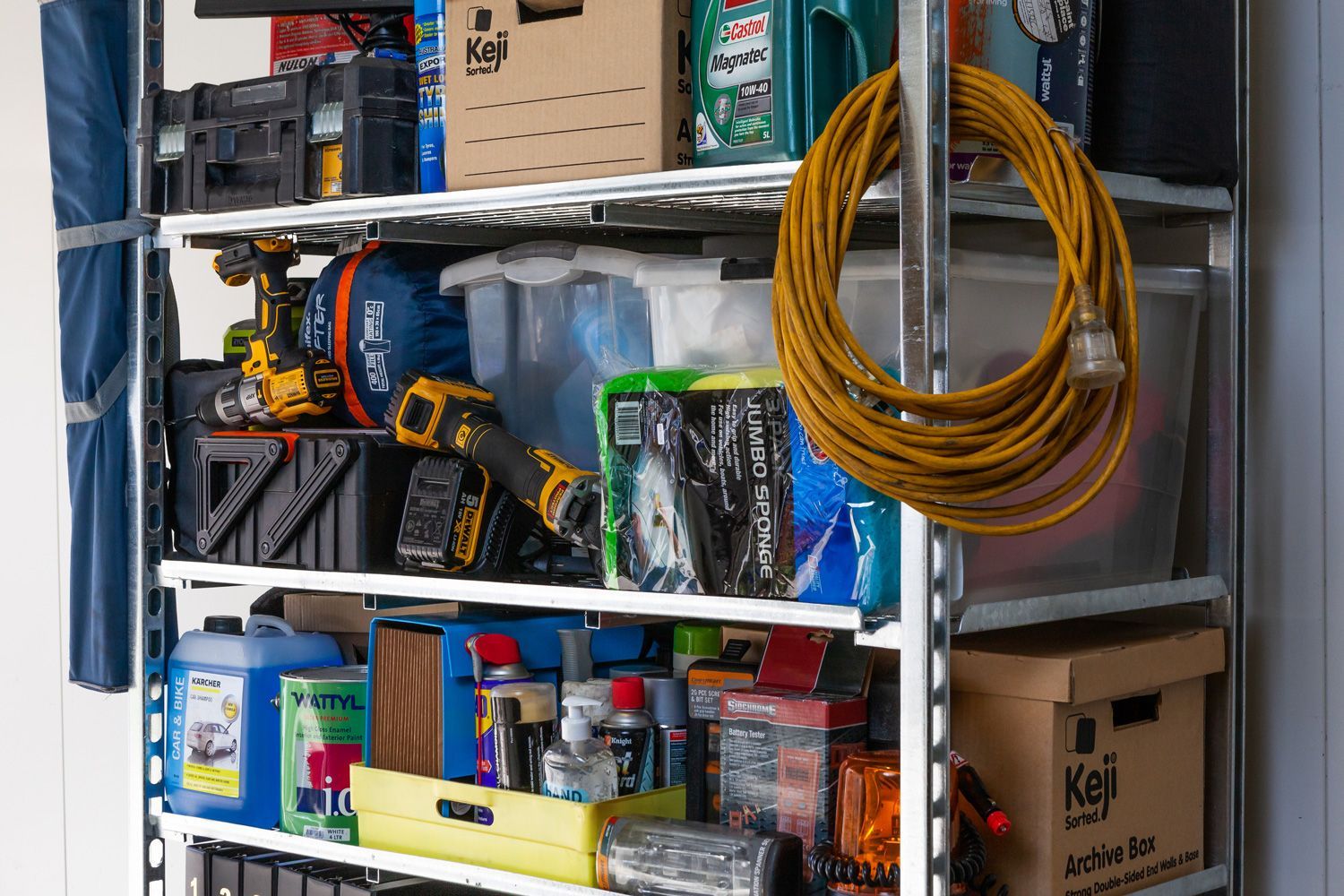 A blue car is parked next to a shelf in a garage.