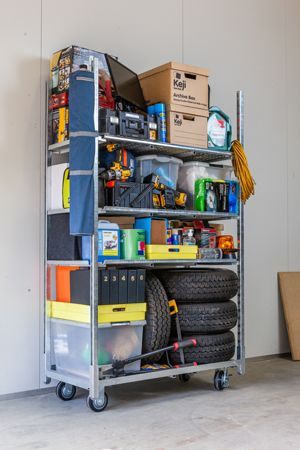 A metal cart filled with lots of items in a garage.