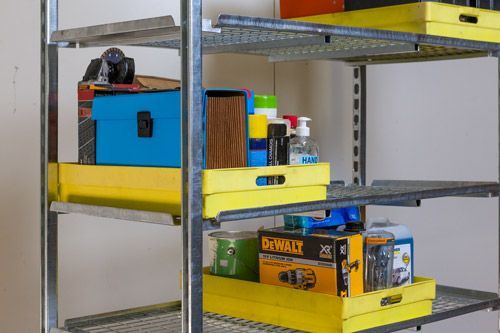 A metal shelf filled with tools and boxes in a garage.