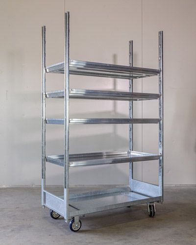 A metal cart with wheels and shelves is sitting in a room.