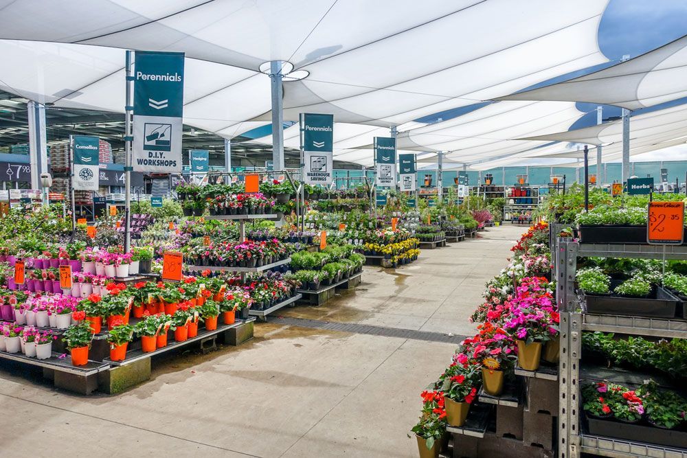 A garden center filled with lots of potted plants and umbrellas.