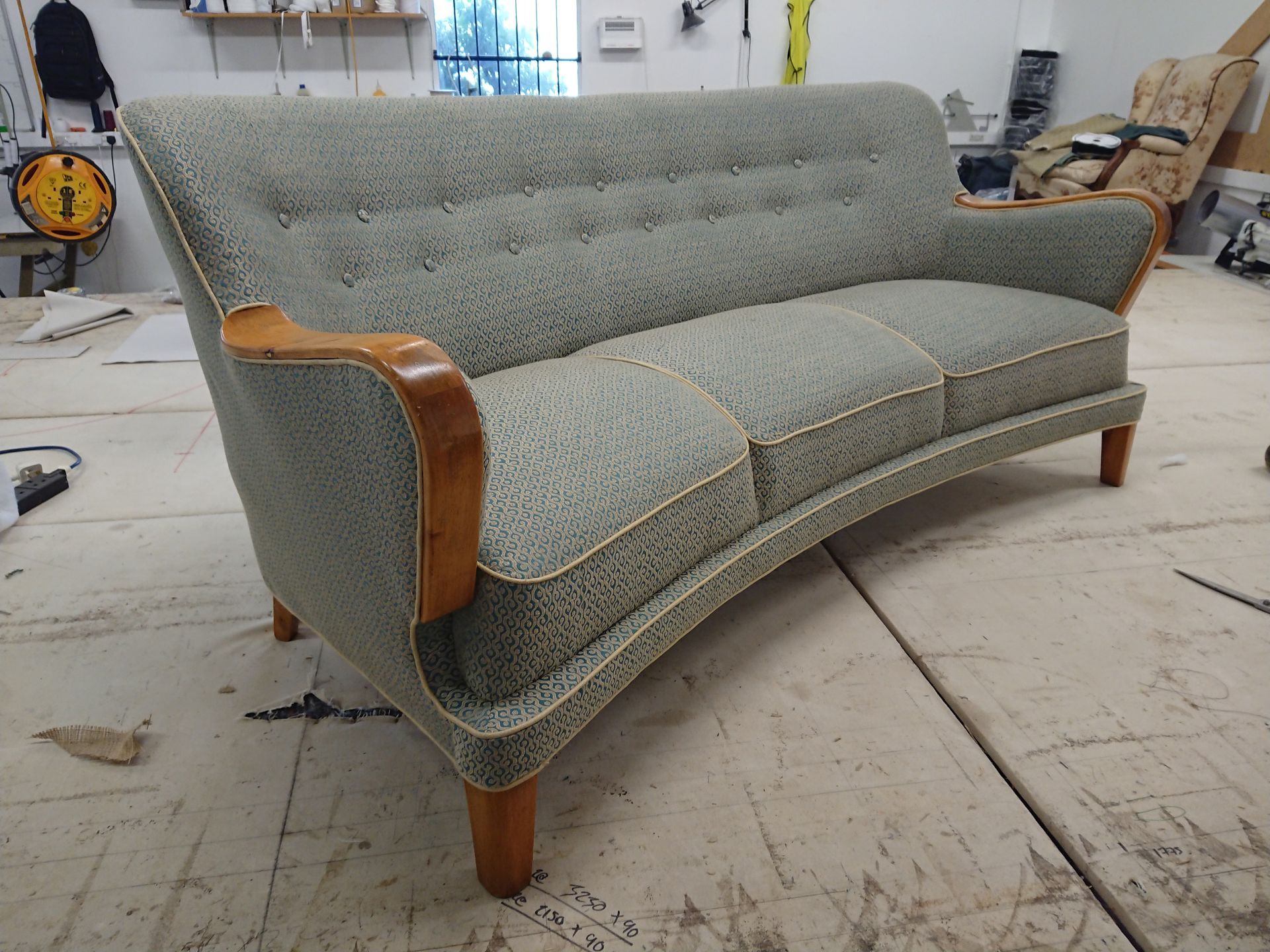 A mid century sofa decorated with green fabric.