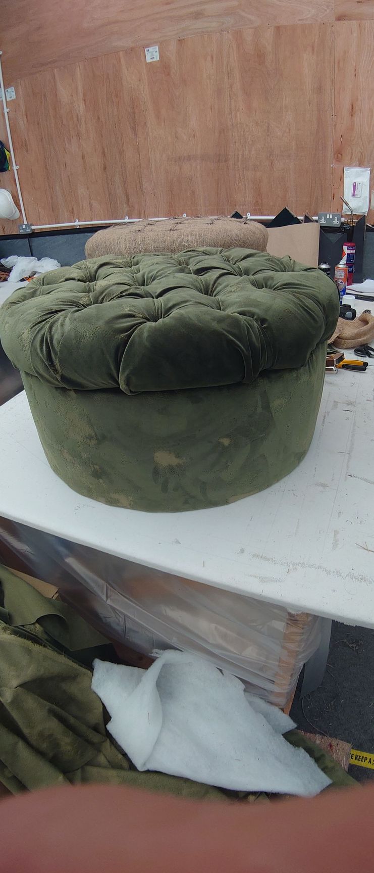 A loosely upholstered , green velvet pouffe.