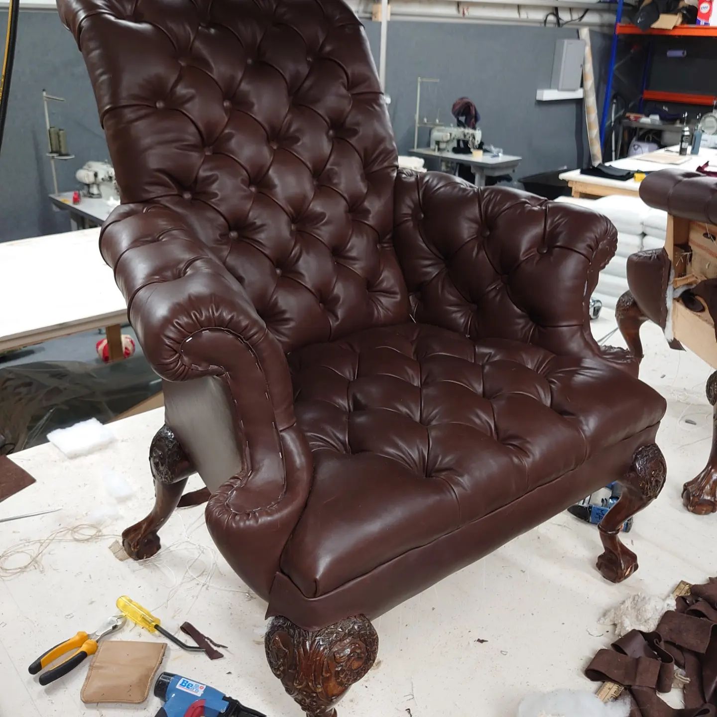A deep buttoned,  brown, leather, wing back chair.