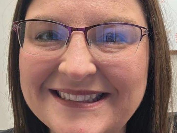 Woman with glasses, smiling, looking directly at the camera.