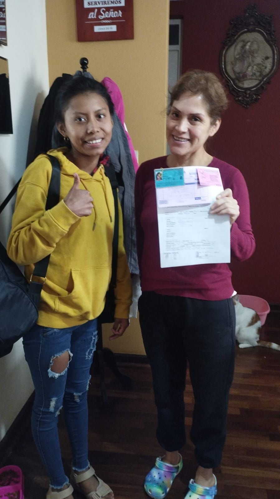 Cuatro personas posando en el interior, sonriendo y sosteniendo papeles, con un cuadro enmarcado 