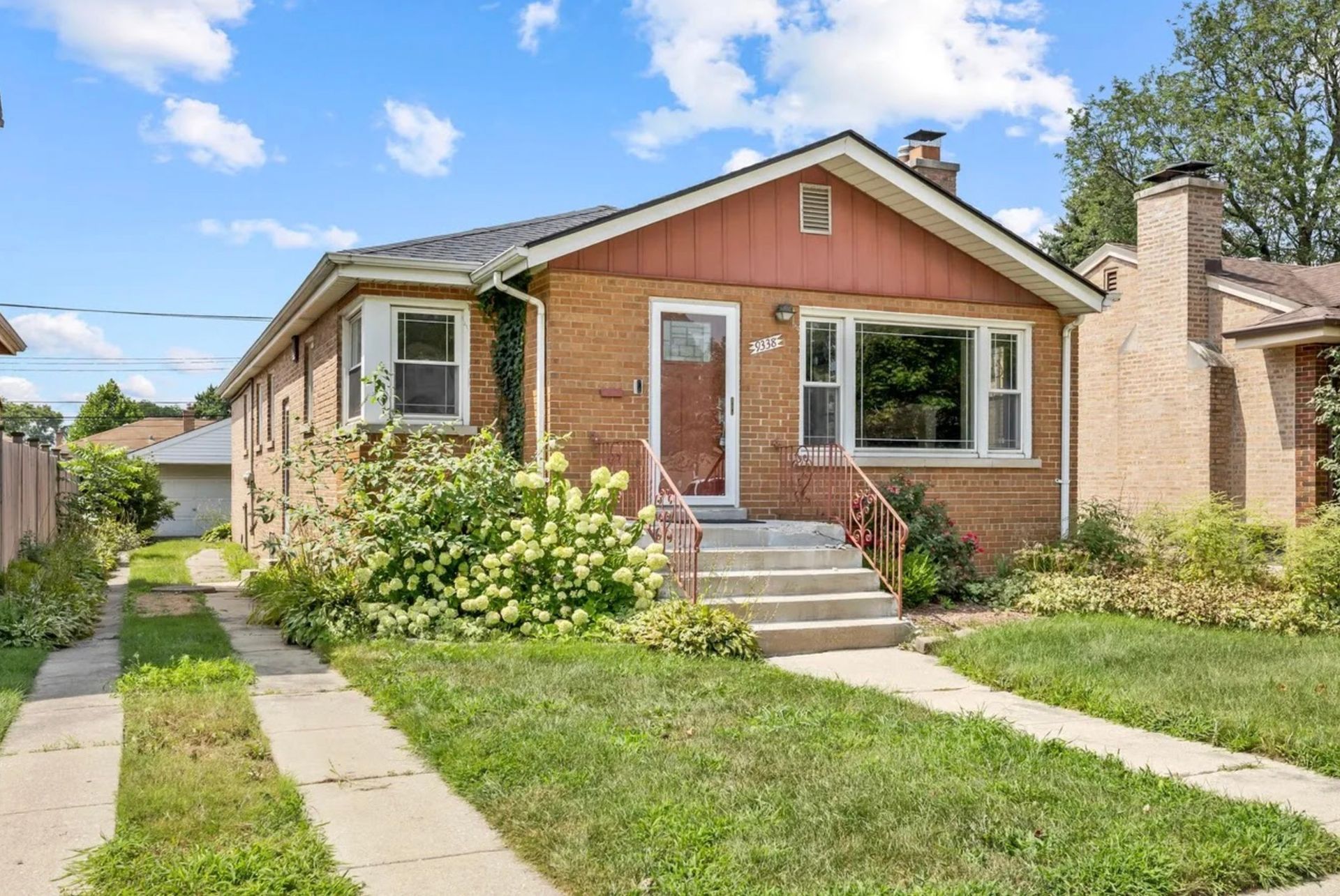 Row of brick houses with front porches on a sunny residential street.