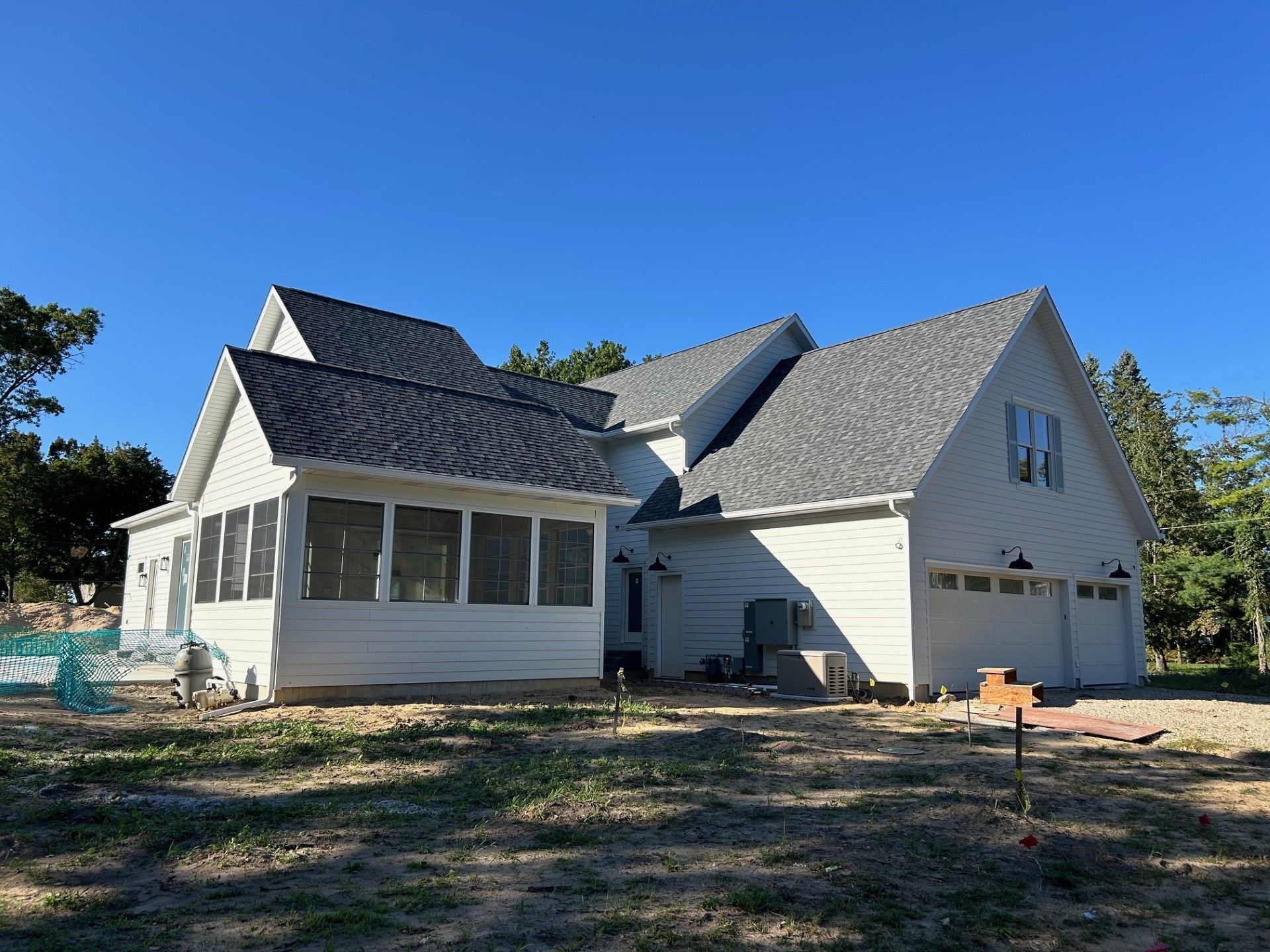 A large white house with a screened in porch and a garage.