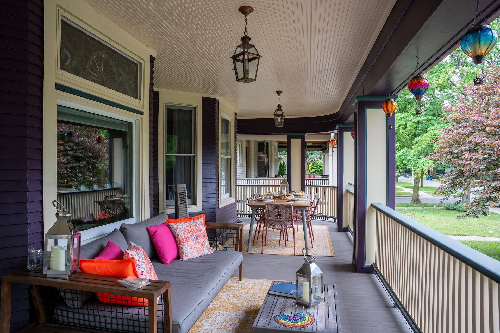A porch with a couch , table and chairs on it.