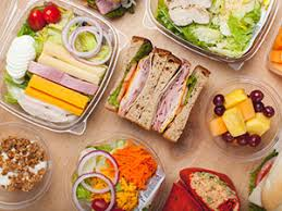 Assortment of pre-packaged lunches: salads, sandwiches, fruits, and yogurt in clear containers.
