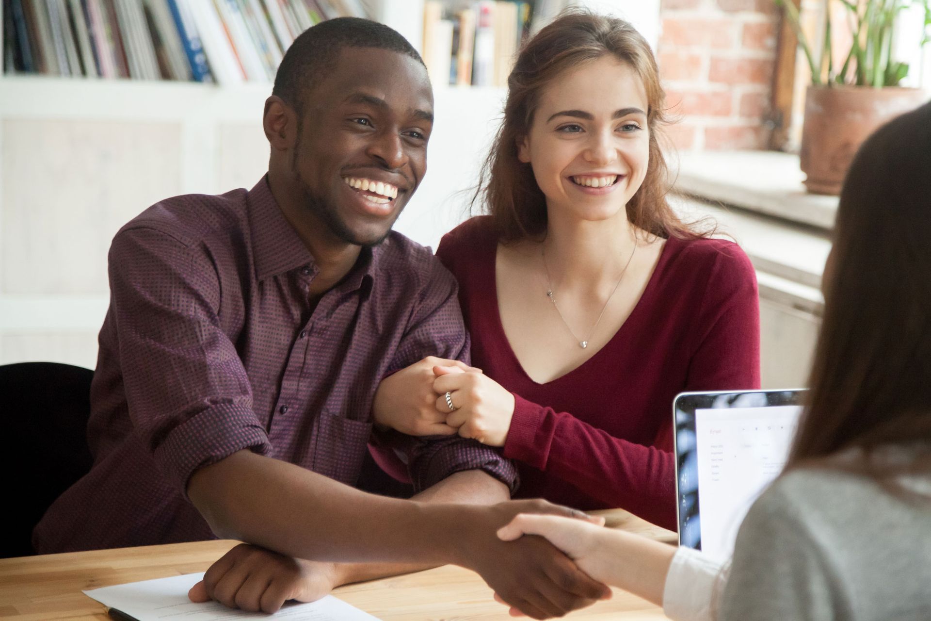 A man and woman are shaking hands with a woman while sitting at a table.