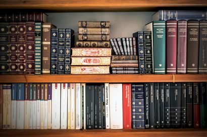 Bookshelves filled with various hardcover books, in a wooden cabinet.