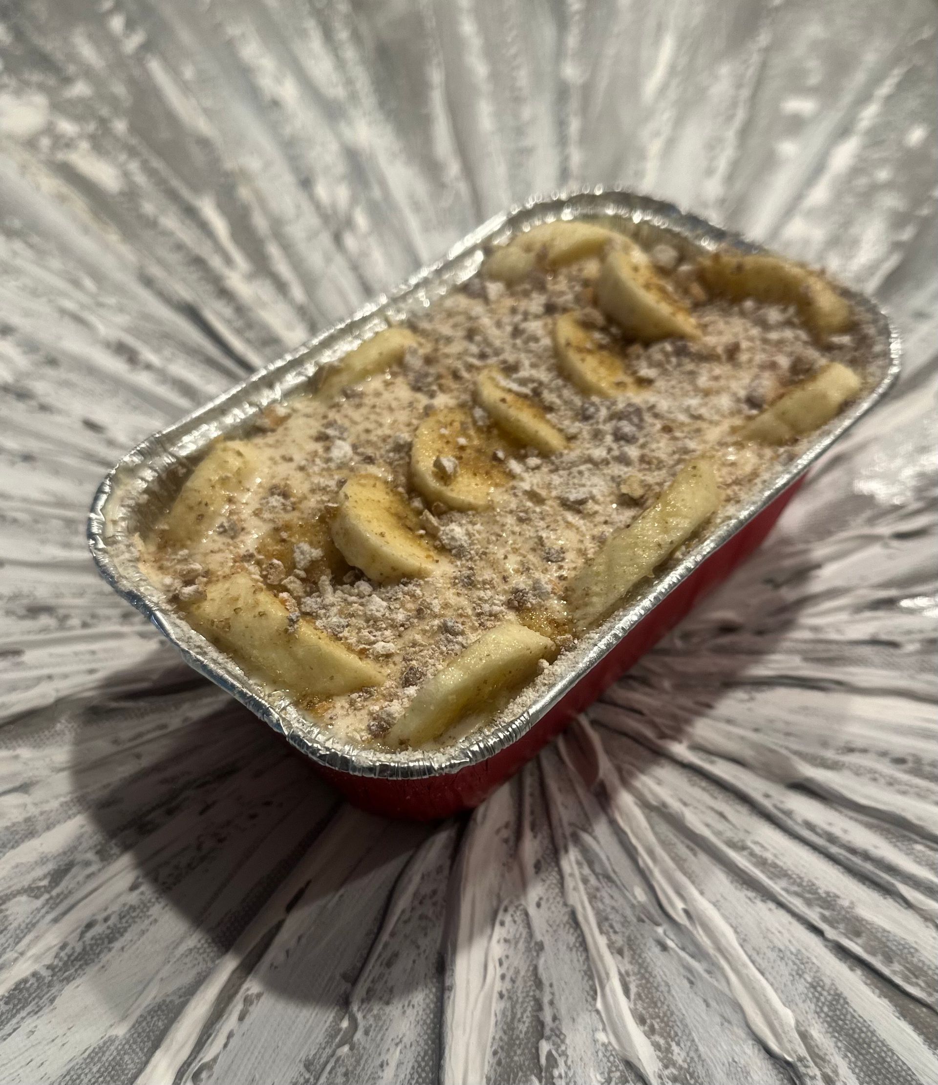 A small tin foil container filled with bananas and oats.