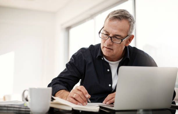 A man is sitting at a desk using a laptop computer.